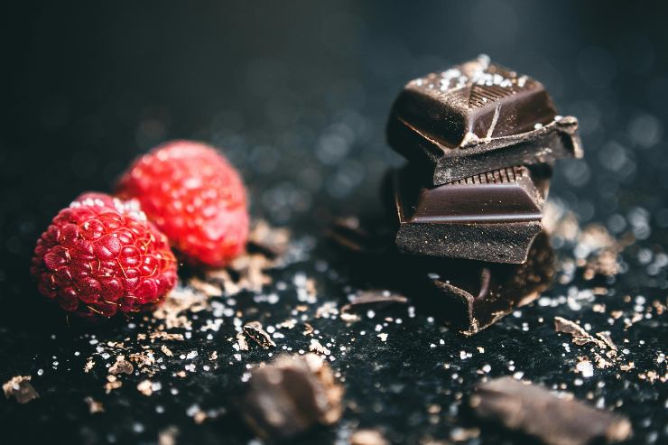 pezzi di cioccolato accanto a due lamponi