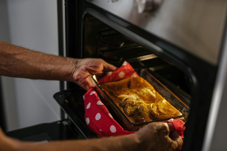 persona che tira una teglia fuori dal forno