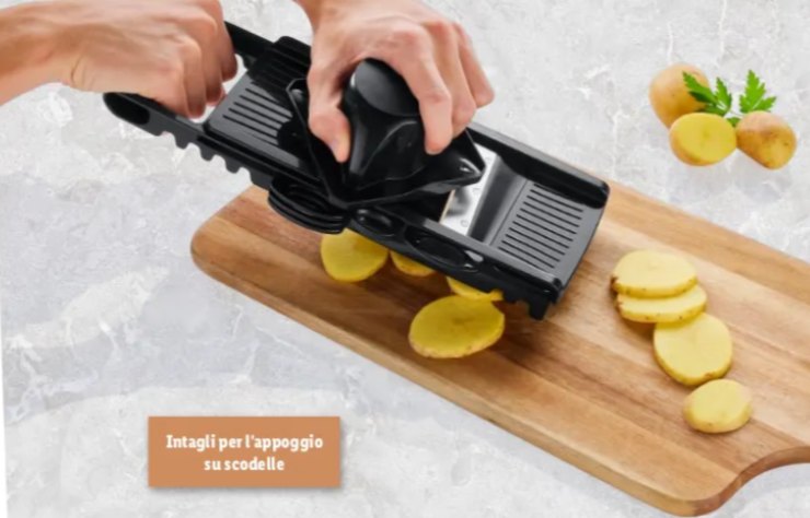 persona che affetta una patata con la mandolina sopra ad un tagliere di legno