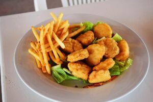 nuggets su un piatto con insalata e patatine fritte