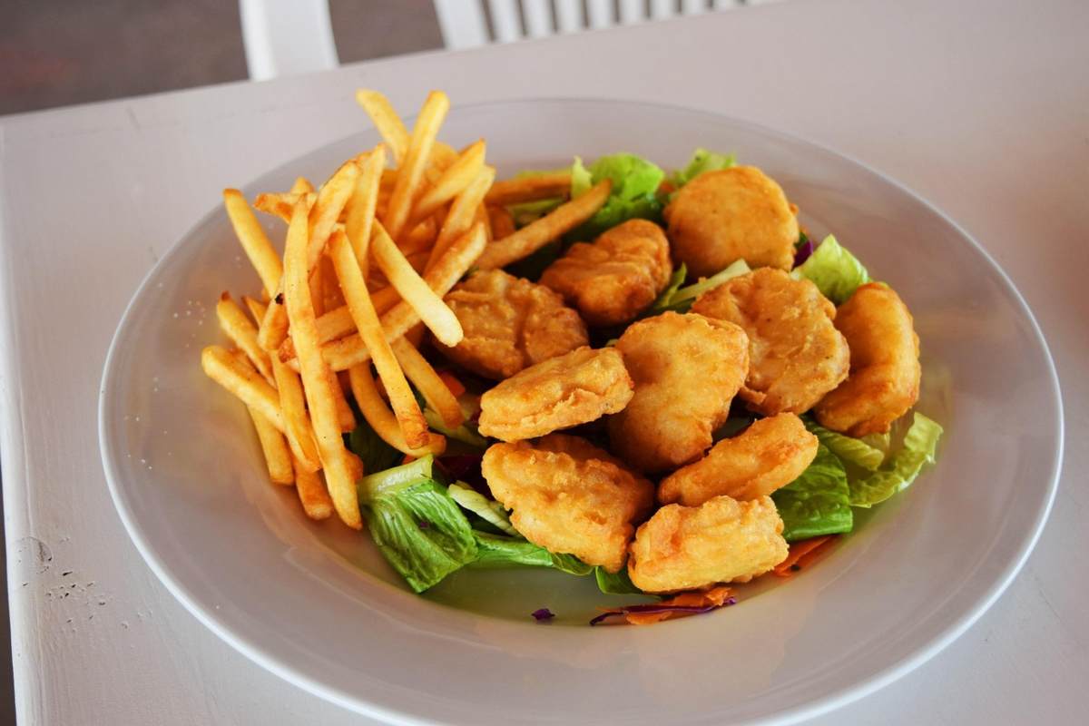 nuggets su un piatto con insalata e patatine fritte