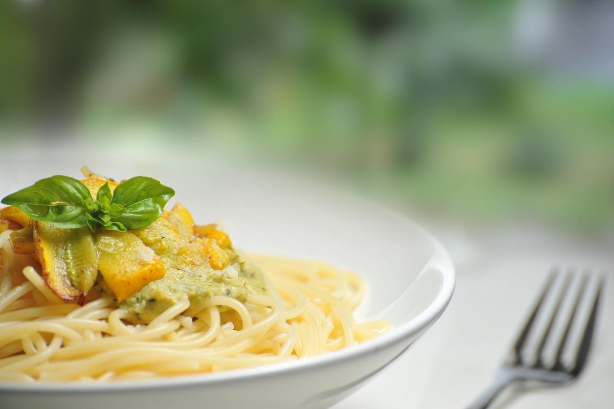 piatto di spaghetti con pesto, foglioline di basilico e scorze di limone