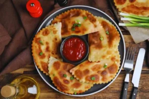 chebureki su un piatto con al centro una salsa