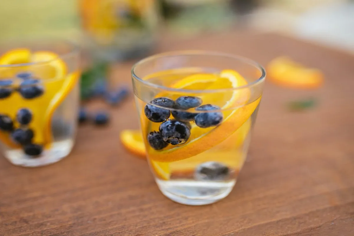 Bicchiere acqua con arancia e mirtilli