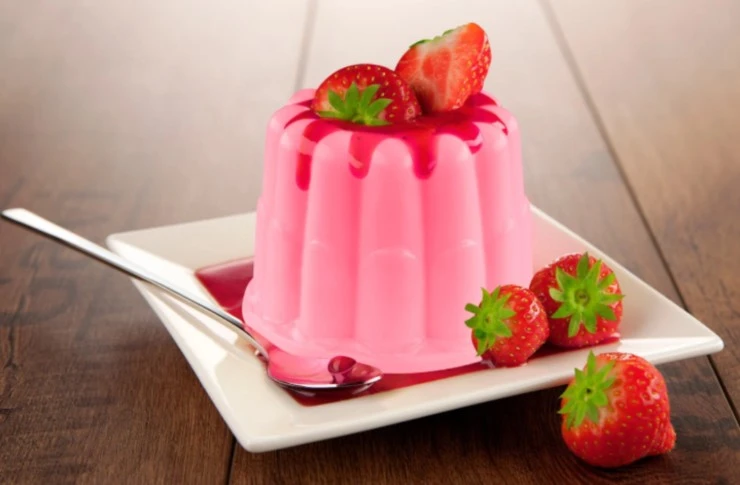 budino alle fragole su un piattino con accanto fragole fresche e un cucchiaino
