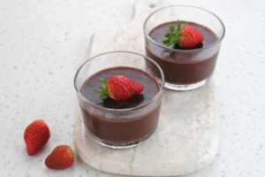 due budini al cacao dentro due bicchieri di vetro con sopra delle fragole