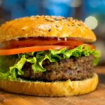 panino con dentro un burger, pomodori e insalata