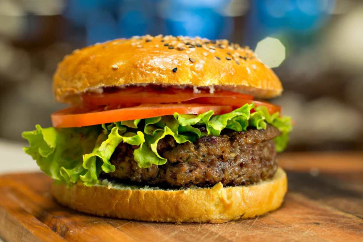 panino con dentro un burger, pomodori e insalata