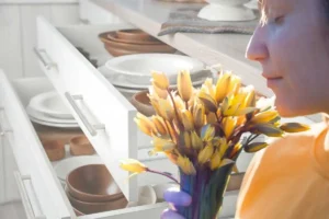 una ragazza che annusa dei fiori e i cassetti della cucina