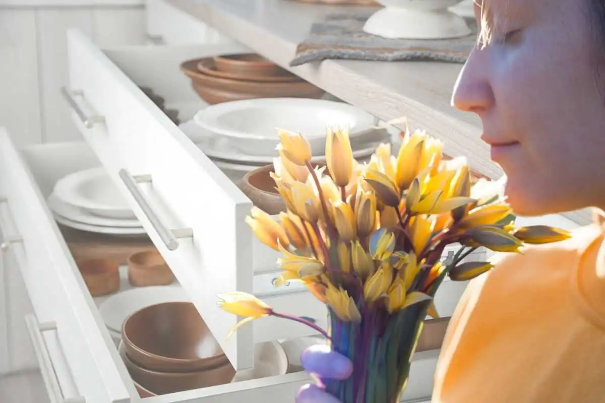 una ragazza che annusa dei fiori e i cassetti della cucina