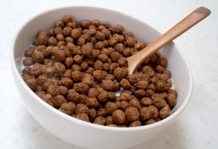 tazza piena di cereali da colazione al cacao con dentro un cucchiaio