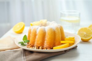 ciambellone dolce sopra ad un piatto con accanto delle fettine di limone