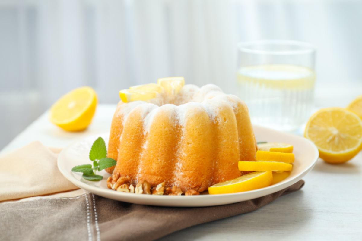 ciambellone dolce sopra ad un piatto con accanto delle fettine di limone