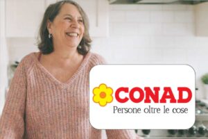 donna che sorride in cucina e logo conad
