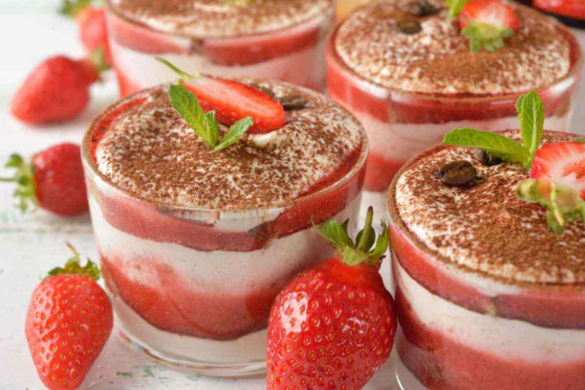 coppette di tiramisù alle fragole con accanto delle fragole fresche