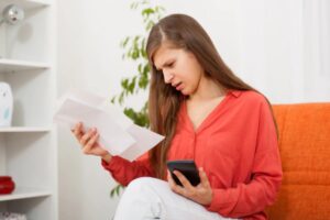 donna seduta sul divano che legge dei fogli con espressione perplessa
