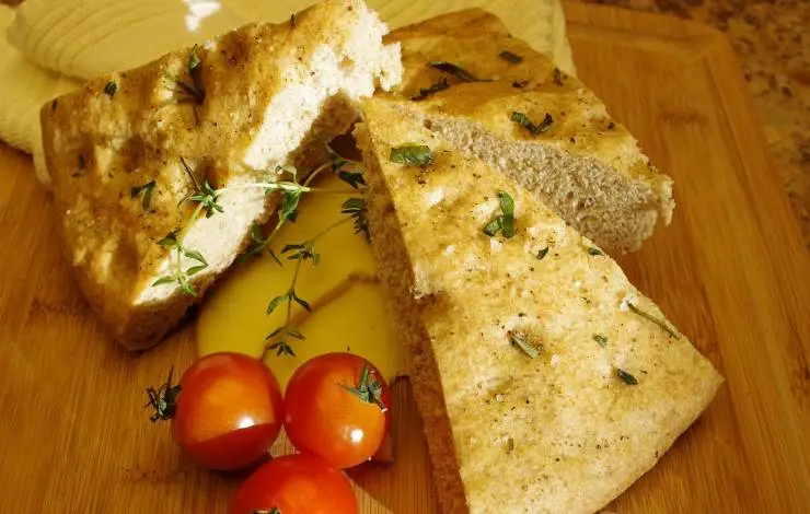 triangoli di focaccia con le erbe e accanto dei pomodori