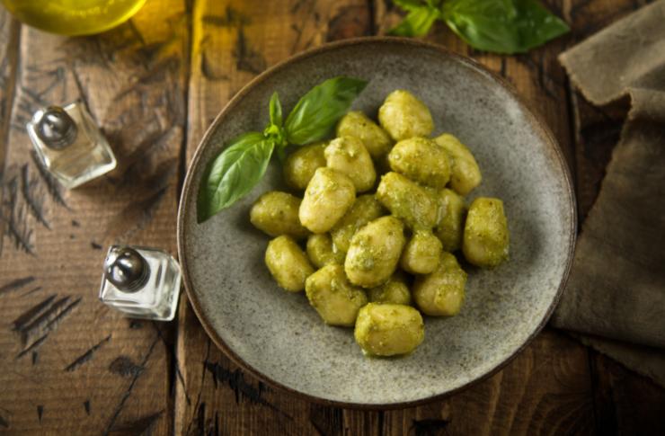 gnocchi al pesto in un piatto e accanto il contenitore del sale