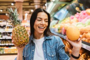 donna sorridente con in mano un ananas e nell'altra mano un agrume