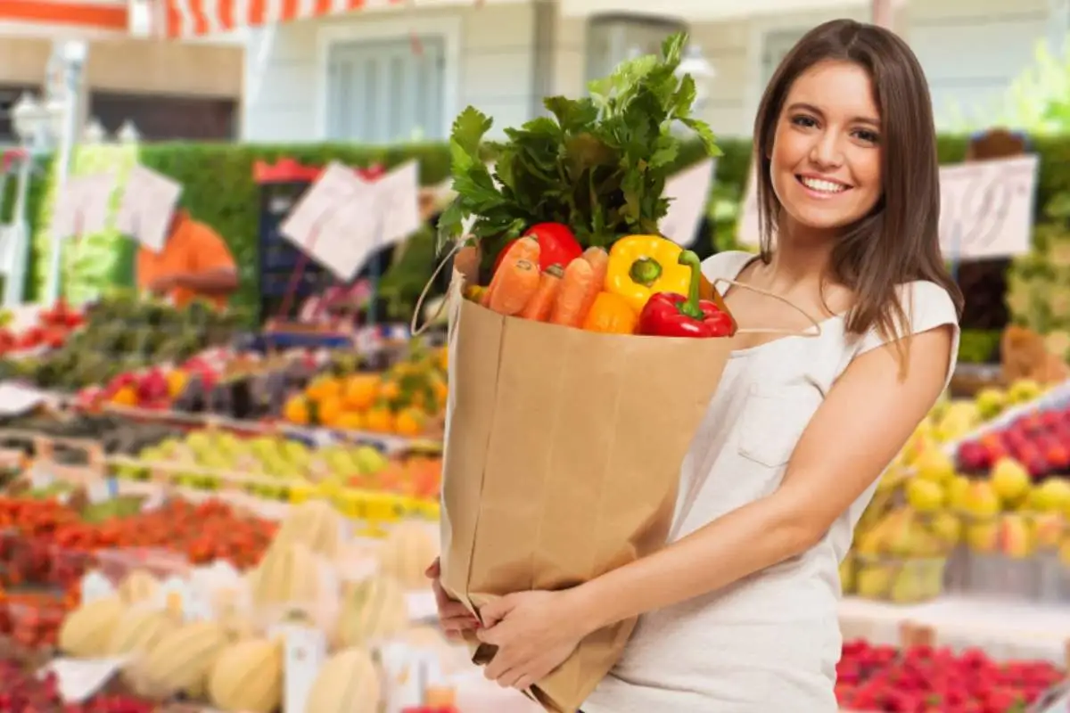 donna con in mano una borsa piena di ortaggi