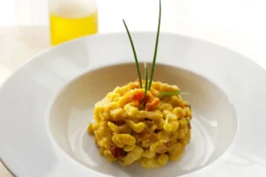 pasta condita con un pesto giallo e sopra dei fili di erba cipollina