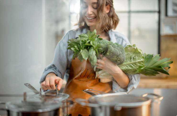donna che cucina e tiene in mano delle verdure