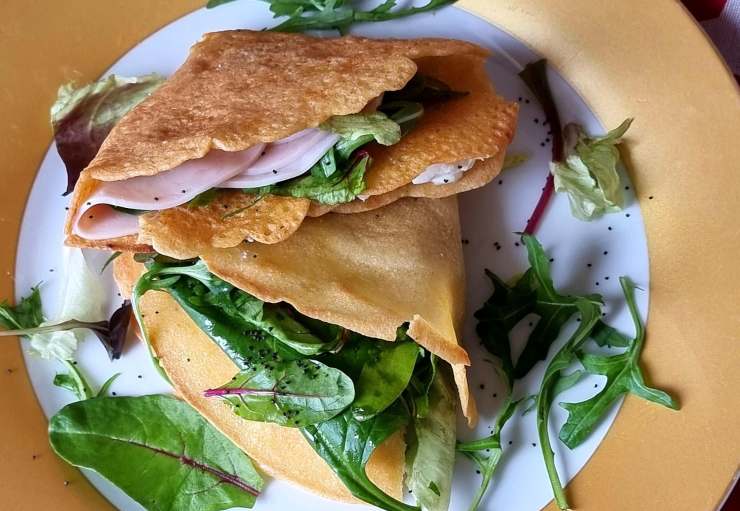 due piadine farcite sopra ad un piatto con intorno foglie di spinaci