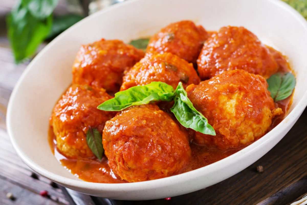 polpette al sugo dentro ad un piatto con sopra delle foglie di basilico