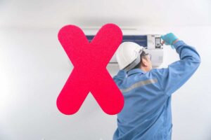 un tecnico che apre un climatizzatore e una x rossa