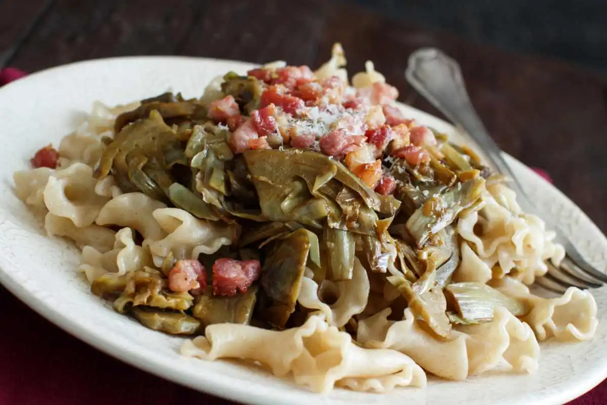 Piatto di pasta con carciofi, pancetta e formaggio grattugiato