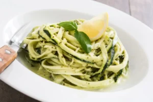 spaghetti di zucchine con sopra una fettina di limone e del basilico