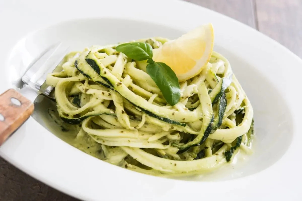 spaghetti di zucchine con sopra una fettina di limone e del basilico