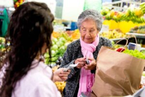donna anziana che paga alla cassa del supermercato