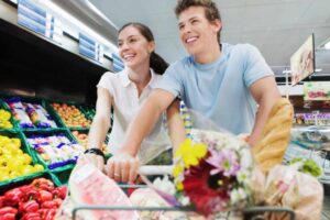uomo e donna che sorridono mentre spingono il carrello al supermercato