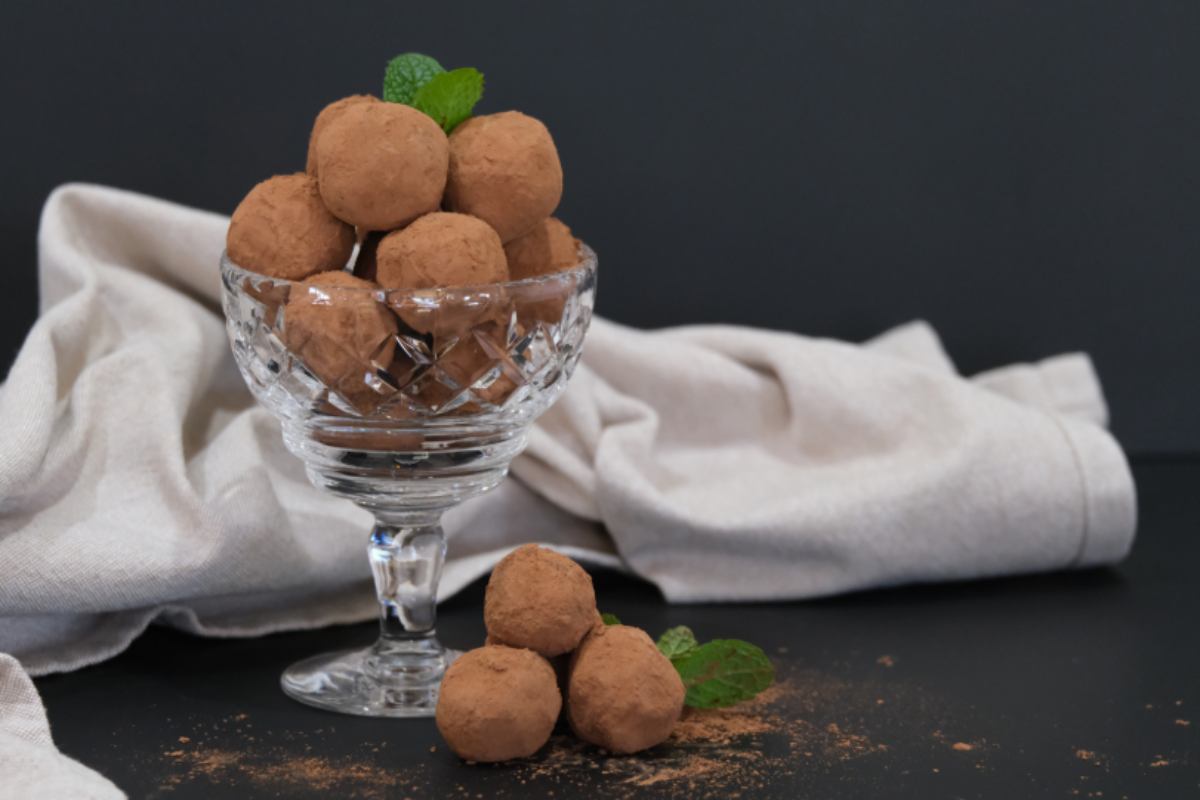 tartufini al cacao dentro ad una coppa di vetro con sopra una fogliolina di menta