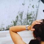 ragazza guarda la muffa in bagno sul muro