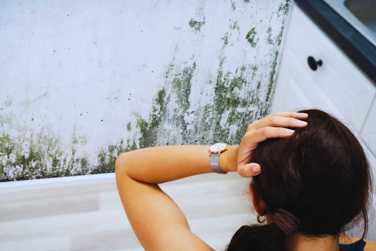 ragazza guarda la muffa in bagno sul muro