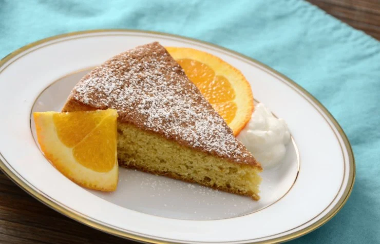 fetta di torta su un piatto con accanto due fette di arancia
