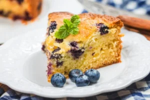 fetta di torta ai mirtilli su un piatto con accanto dei mirtilli