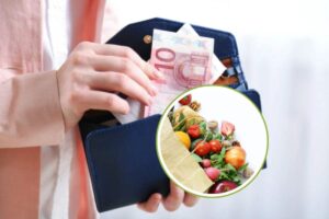 mani con portafoglio e frutta in miniatura