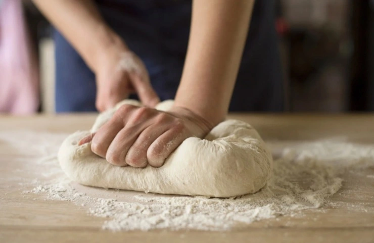 persona che impasta su un tagliere di legno