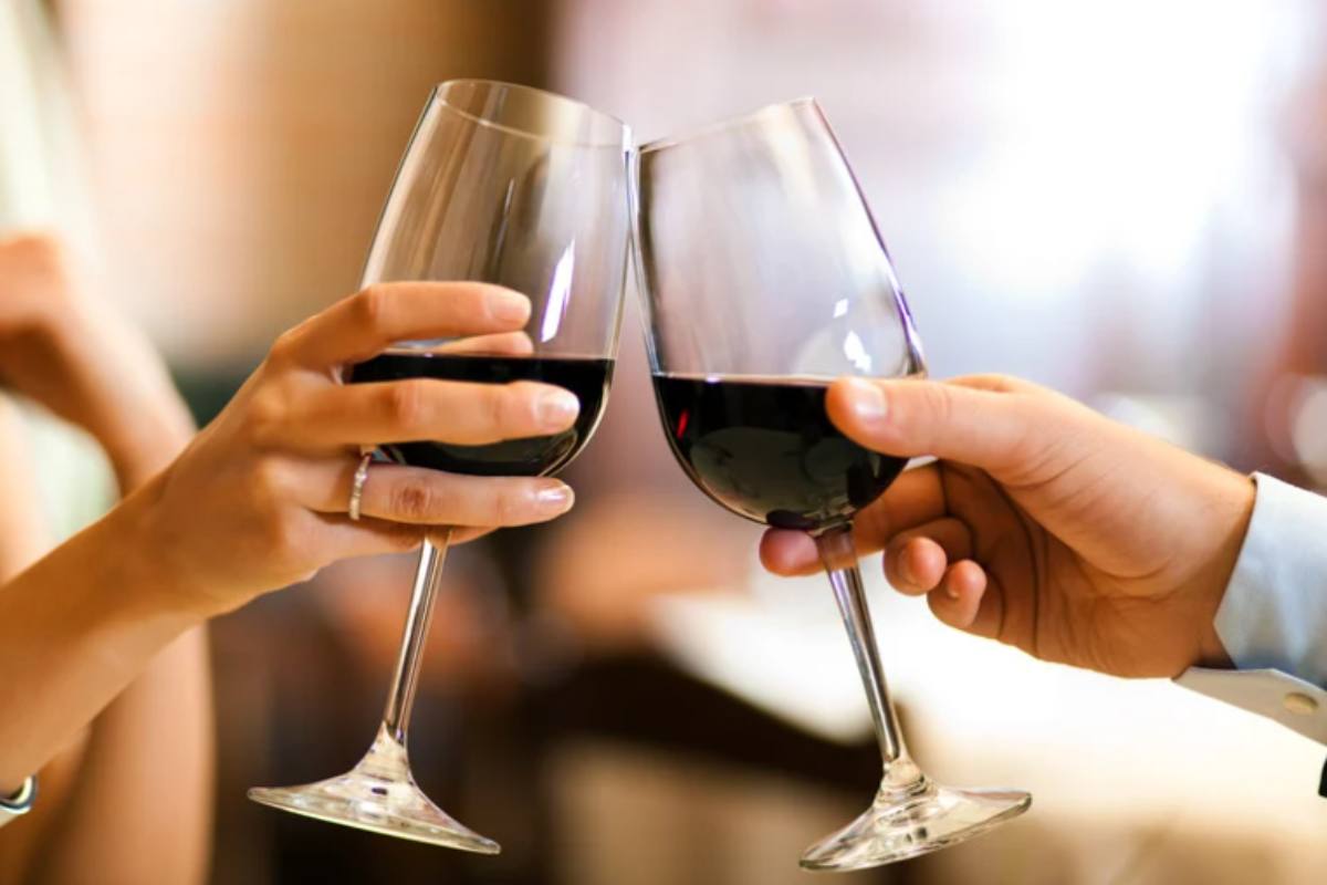 persone che brindano con due calici di vino