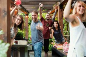 ragazzi e ragazze che alzano i bicchieri e sorridono mentre fanno festa