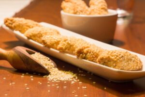 biscotti sopra ad un piatto e accanto un mestolo con dentro semi di sesamo