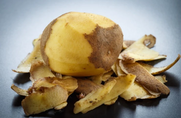 patata sbucciata con accanto la sua buccia
