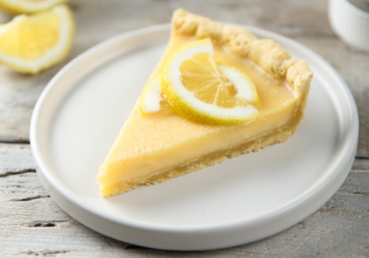 fetta di crostata su un piatto con sopra una fettina di limone