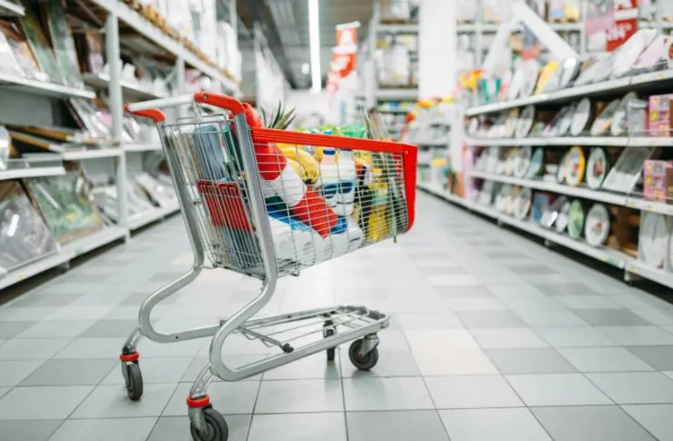 carrello pieno di cibo in mezzo ad una corsia del supermercato