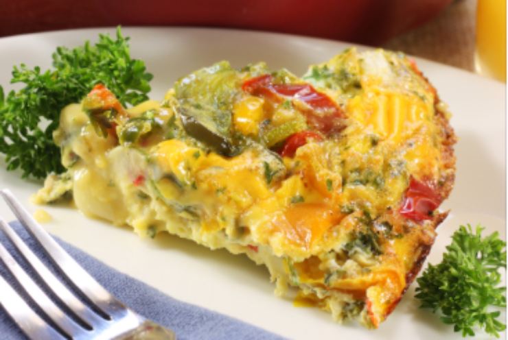 fetta di torta salata di verdure sopra ad un piatto e accanto una forchetta