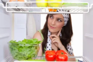 donna che guarda dentro al frigo