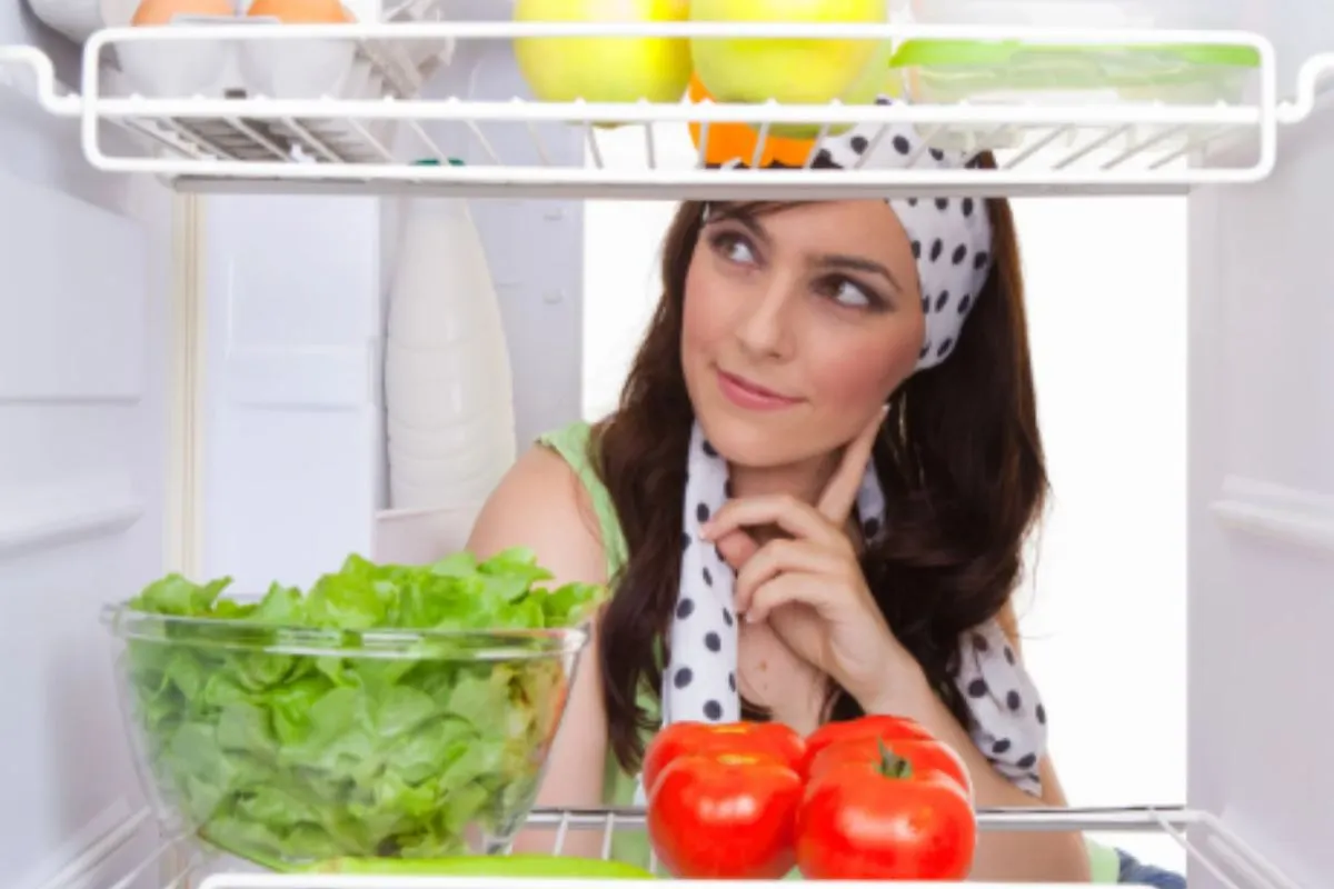donna che guarda dentro al frigo